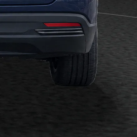 Close-up of the SUV’s rear tyre on the studio’s dark carpet, seen from behind, with the contact shadow under the car.