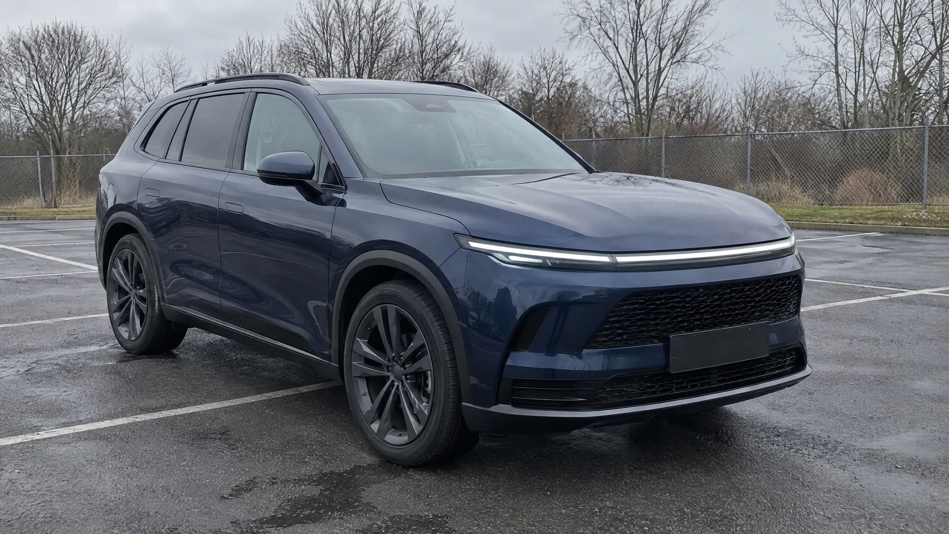 A fictional dark blue SUV on a wet, empty car lot under a grey sky, front three-quarter view; a sample photo made with TunePixel AI.